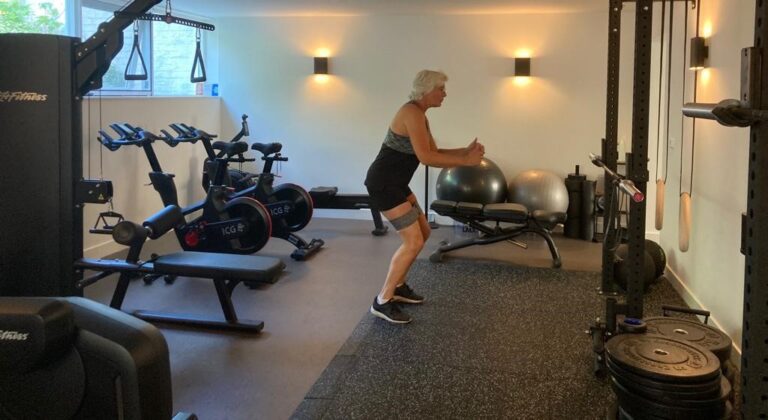 Oudere fitte vrouw in sportkleding traint in haar gym thuis