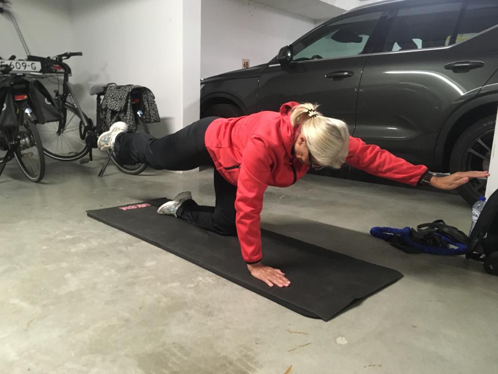Oudere fitte dame in sportkleding traint op een matje in haar garage