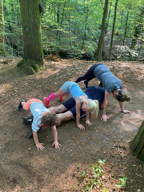 Vrouw en haar 2 kinderen in sportkleding trainen buiten in het bos