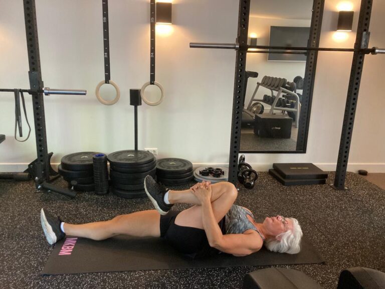 Oudere fitte vrouw in sportkleding traint thuis in haar eigen gym