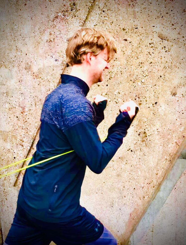 Man in sportkleding traint hard buiten, dmv een elastiek