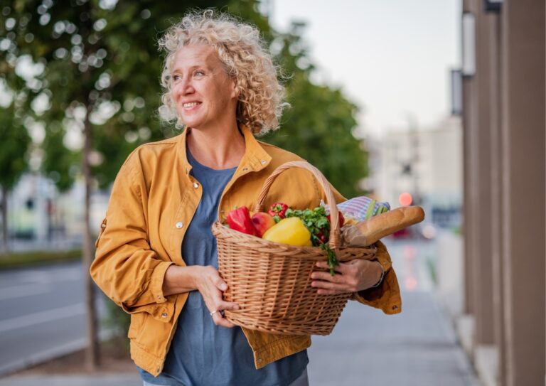 Vitale 40 plus vrouw, houdt een fruitmand vast en kijkt van haar af